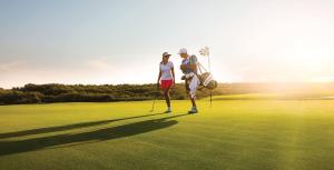 Ein Mann und eine Frau stehen auf einem Golfplatz in der Unterkunft Zoya Health & Wellbeing Resort in Ajman 