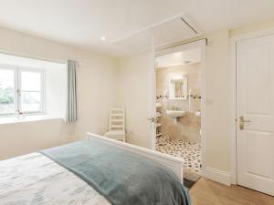 a white bedroom with a bed and a bathroom at Hebe in Dorchester