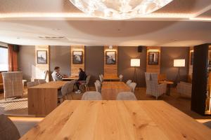 two people sitting at tables in a restaurant at The Lodge Sporthotel - Golfclub Eppan in Appiano sulla Strada del Vino