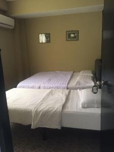 una camera con due letti con lenzuola bianche di Tabin Lodge a Lahad Datu