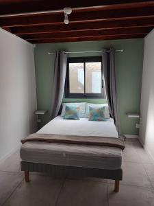 Bett in einem Zimmer mit Fenster in der Unterkunft Ti Kaz Fond de Puits in Saint-Philippe