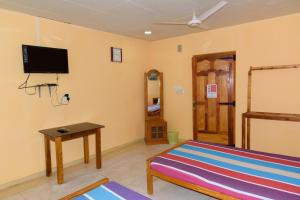um quarto com uma cama e uma televisão de ecrã plano em Gnanam Holiday Inn em Pasikuda