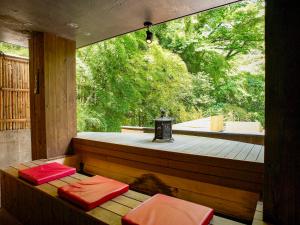 una terraza con 2 sillas acolchadas rojas en un porche de madera en Seikansou, en Hakone