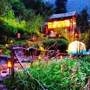 a house with lights in a garden at night at Parvatis Lap Luxury Hostel & Camps in Kasol
