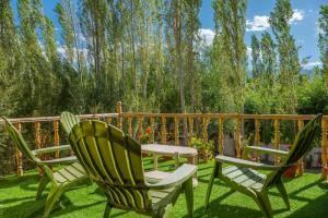 three chairs and a table on a lawn at Maney Homestay - Thiksey - Leh in Ranbirpura +17 photos