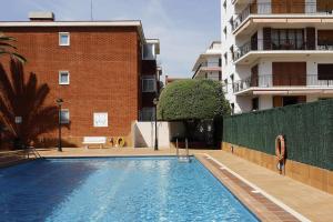 a woman is standing next to a swimming pool in a building at AT085 Germandat in Torredembarra