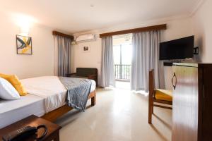 a hotel room with a bed and a television at Raposo Resorts in Vagator