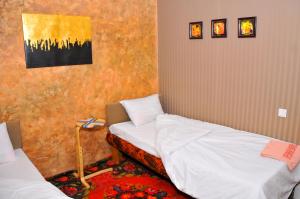 a bedroom with two beds and a painting on the wall at Art House Sweet home in Shymkent