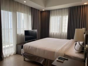 a bedroom with a bed and a tv and windows at The Residences at BCCT in Manila