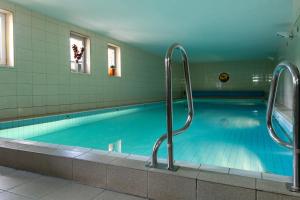 a swimming pool with blue water in a building at MADOHORA ŚLEMIEŃ in Kocoń