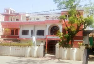 a red brick house with a white fence in front of it at Jwala Niketan Guesthouse Private rooms in Jaipur