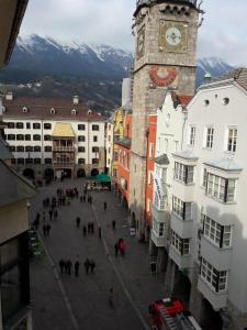 um grupo de pessoas andando em torno de uma cidade com uma torre do relógio em Blick aufs Goldene Dachl em Innsbruck