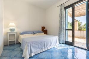 a white bedroom with a bed and a large window at Sogno Mediterraneo Pula Sardegna villa a soli 300 mt dal mare in Porto Columbu - Perdʼe Sali