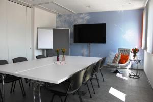 a meeting room with a large white table and chairs at AIS Center in Wolfsberg