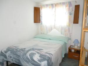 ein kleines Schlafzimmer mit einem Bett und einem Fenster in der Unterkunft Attico Bellavista in Santa Maria Navarrese