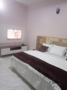 een slaapkamer met een groot bed en een tv aan de muur bij Captivating 1-Bed Studio in Sapele in Sapele