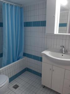 a bathroom with a blue shower curtain and a sink at Cozy flat in Nea Makri in Nea Makri
