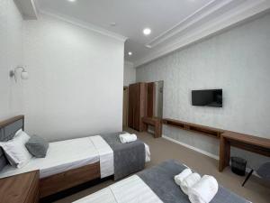 Habitación de hotel con 2 camas y TV de pantalla plana. en Emin hotel, en Ferganá