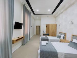 um quarto de hotel com duas camas e uma televisão em Emin hotel em Fergana