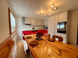 貝特默阿爾卑的住宿－Chalet Diana - Spacious flat - Village core - South facing - Ski-in/Ski-out，厨房配有木桌和红色橱柜。