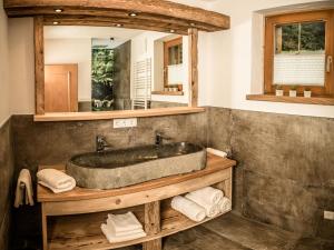 La salle de bains est pourvue d'un lavabo en pierre et d'un miroir. dans l'établissement Chalet Eben, à Eben im Pongau