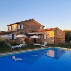 a villa with a swimming pool in front of a house at Casale Papa Country Village in Loreto