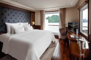 - une chambre avec un grand lit blanc et une fenêtre dans l'établissement Paradise Elegance Cruise Halong, à Hạ Long