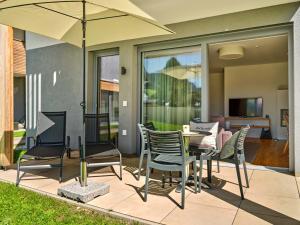 a patio with a table and chairs and an umbrella at die Tauplitz Lodges - Wasserfall Lodge C1 by AA Holiday Homes in Tauplitz
