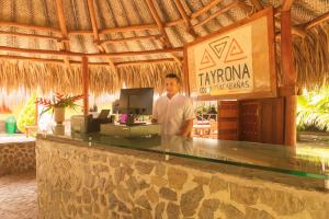 Ein Mann steht hinter einer Bar in einem Resort. in der Unterkunft Camping Tequendama Playa Arrecifes Parque Tayrona in El Zaino