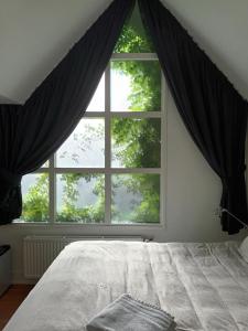 a bedroom with a large window with black curtains at Prins Heerlijk in Sassenheim