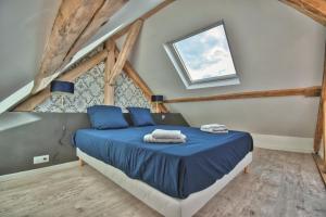 a bedroom with a bed with blue sheets and a window at * Le Duplex * in Maintenon