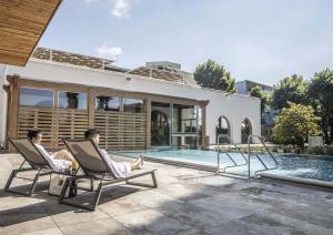 two men sitting in chairs next to a swimming pool at Hotel Fontana Olente in Ferentino