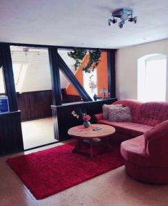 - un salon avec un canapé rouge et une table dans l'établissement Gemütliche 3 Raum Wohnung im Dachgeschoss, à Ehrenfriedersdorf