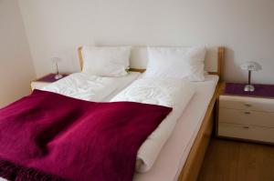 - un grand lit blanc avec une couverture rouge dans l'établissement Ferienwohnung Nordseeglueck, à Hooksiel