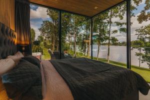 Schlafzimmer mit einem Bett vor einem großen Fenster in der Unterkunft 7Mirrors in Skrīveri