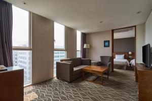 a hotel room with a couch and a bed and a television at Hotel Square Ansan in Ansan