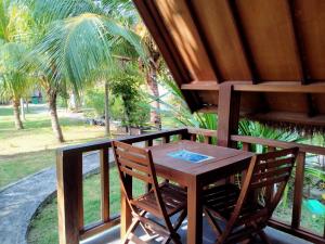 una mesa de madera y sillas en un balcón con una palmera en DEA Gili Cottages, en Gili Meno