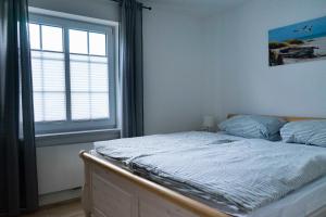 Bett in einem Schlafzimmer mit Fenster in der Unterkunft Ferienwohnung Wassmann Hooksiel in Hooksiel