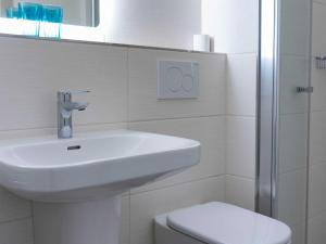 a white bathroom with a sink and a toilet at Ferienwohnung Wassmann Hooksiel in Hooksiel