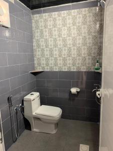 a bathroom with a toilet and a tiled wall at Balcony walk rest house Jabal shams in Sa‘ab Banī Khamīs