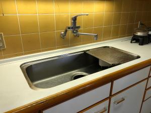 a stainless steel sink in a kitchen with yellow tiles at Cool-Villa 飛騨リゾート in Hida