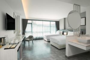 um quarto de hotel com uma cama, um lavatório e um espelho em Livable Hotel Bangkok em Bangkok