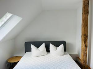 Bett mit weißer Bettwäsche und Kissen in einem Zimmer in der Unterkunft Deich Connect 9.4 in Dorum Neufeld