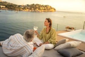 Eine Frau und ein Mann sitzen auf einem Boot mit einem Glas Wein. in der Unterkunft Iberostar Selection Jardín del Sol Suites - Adults Only in Santa Ponsa