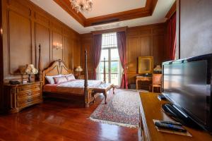 a bedroom with a bed and a flat screen tv at Chateau de Khaoyai Hotel & Resort in Khao Yai