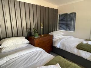 1 dormitorio con 2 camas y tocador de madera en U.R.B.A.N on St. John, en Oudtshoorn