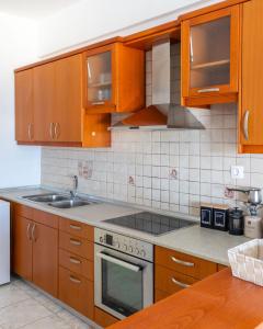 a kitchen with wooden cabinets and a stove top oven at Lovely sea view apartment at the heart of the town in Ierápetra +17 photos