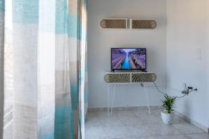a room with a television on a stand in a room at Lovely sea view apartment at the heart of the town in Ierápetra