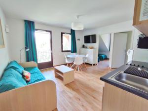 uma sala de estar com um sofá e uma cozinha em Chez Marie-Laure, T3 résidence les Jardins de Ramel, parking, balcon, 4 personnes em Luchon