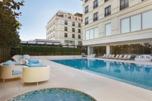 a swimming pool with chairs and a building at Wyndham Grand Istanbul Kalamış Marina Hotel in Istanbul